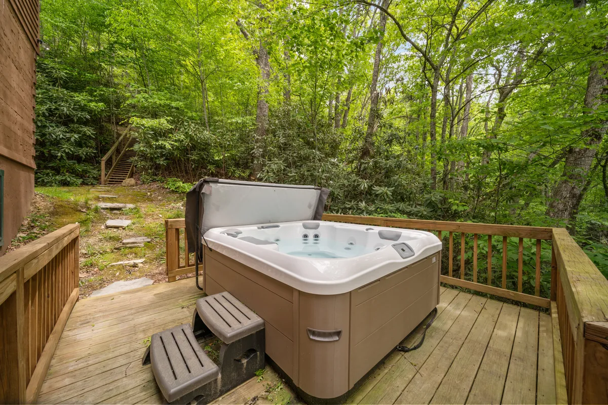 A peaceful outdoor deck featuring a hot tub surrounded by lush greenery. The setting offers a sense of tranquility and is spacious enough for several guests to unwind together while enjoying the natural scenery—ideal for celebrating milestones or relaxing after a day of adventures.