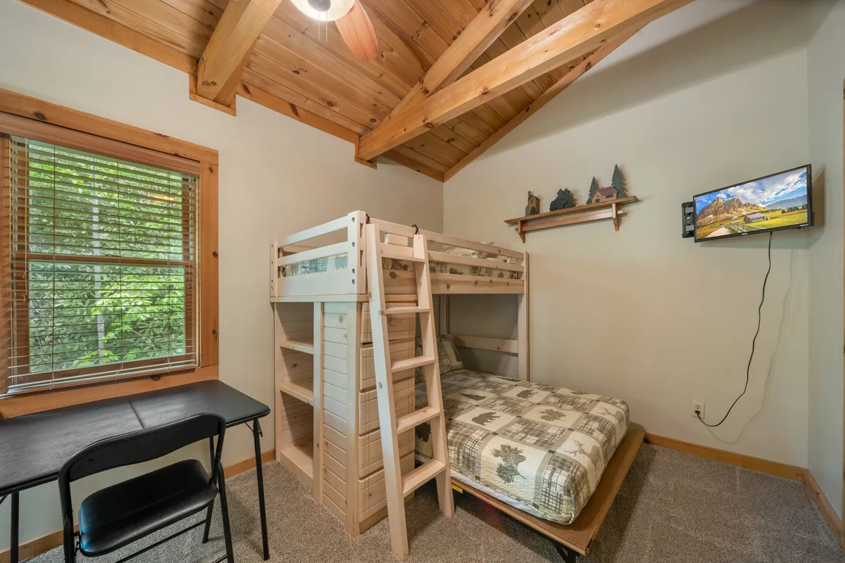 A loft area with a cozy bunk bed, a desk, and a window that lets in ample daylight. The décor suggests an inviting space well-suited for reading, quiet reflection, or playful adventures, perfectly designed for kids or teens.