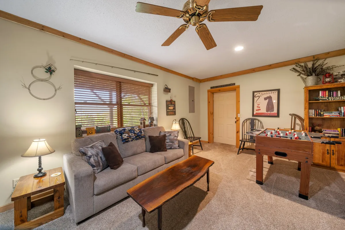 A view of a family-friendly interior featuring a sofa, a coffee table, a foosball table, and a bookshelf. The space is arranged to encourage lounging, playing games, and reading, with plenty of natural light filling the room.